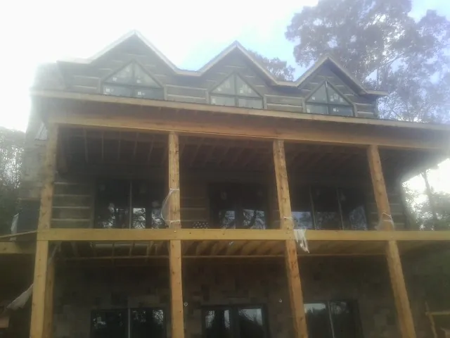Dormers and porch framing on a large log home under construction — Roof Coating work by our crew in Chippewa Falls