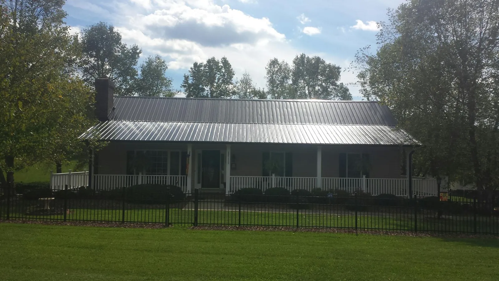 Gray metal roof on a brick ranch with a full width front porch — Gutter Guard Installation work by our crew in Chippewa Falls