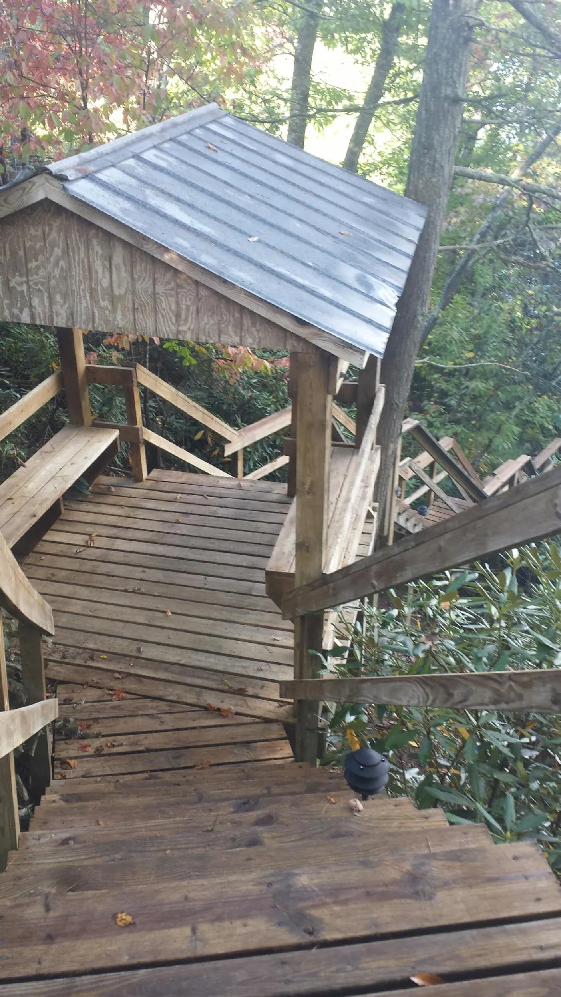 Metal roofed shelter over wooden steps on a wooded walkway — Skylight Repair & Installation work by our crew in Chippewa Falls