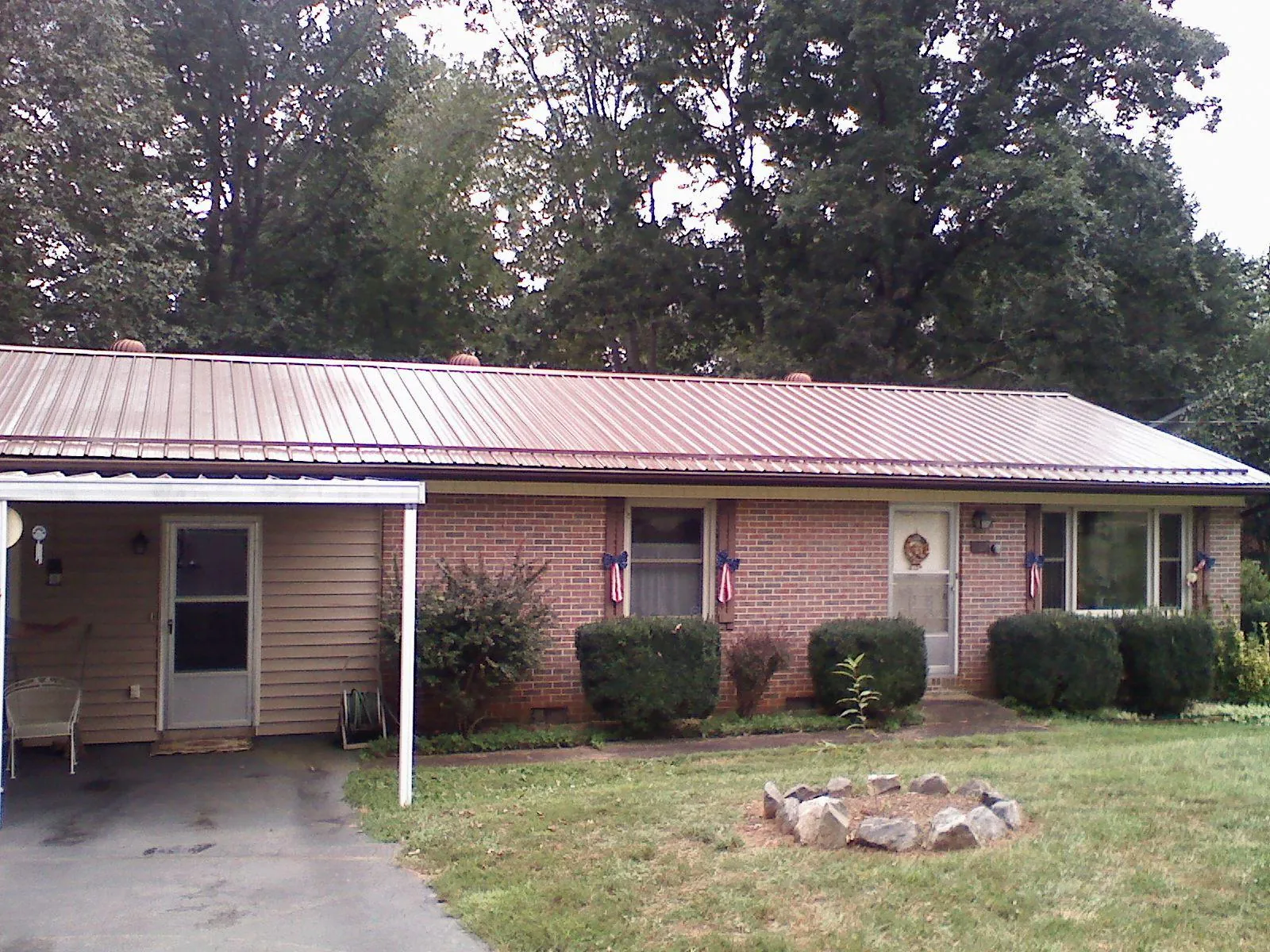 Bronze metal roof and carport on a brick ranch home — Roof Repair work by our crew in Chippewa Falls