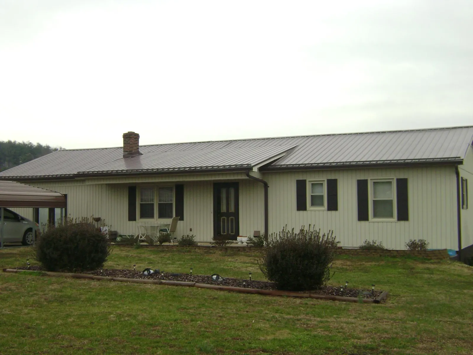 Brown metal roof on a cream sided ranch home with a brick chimney in Chippewa Falls